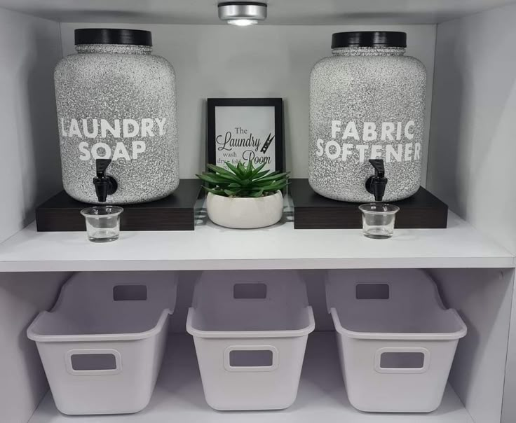 three white storage containers sitting on top of a shelf next to two plastic bins