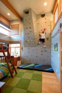 a child climbing up the side of a rock wall in a room with bunk beds