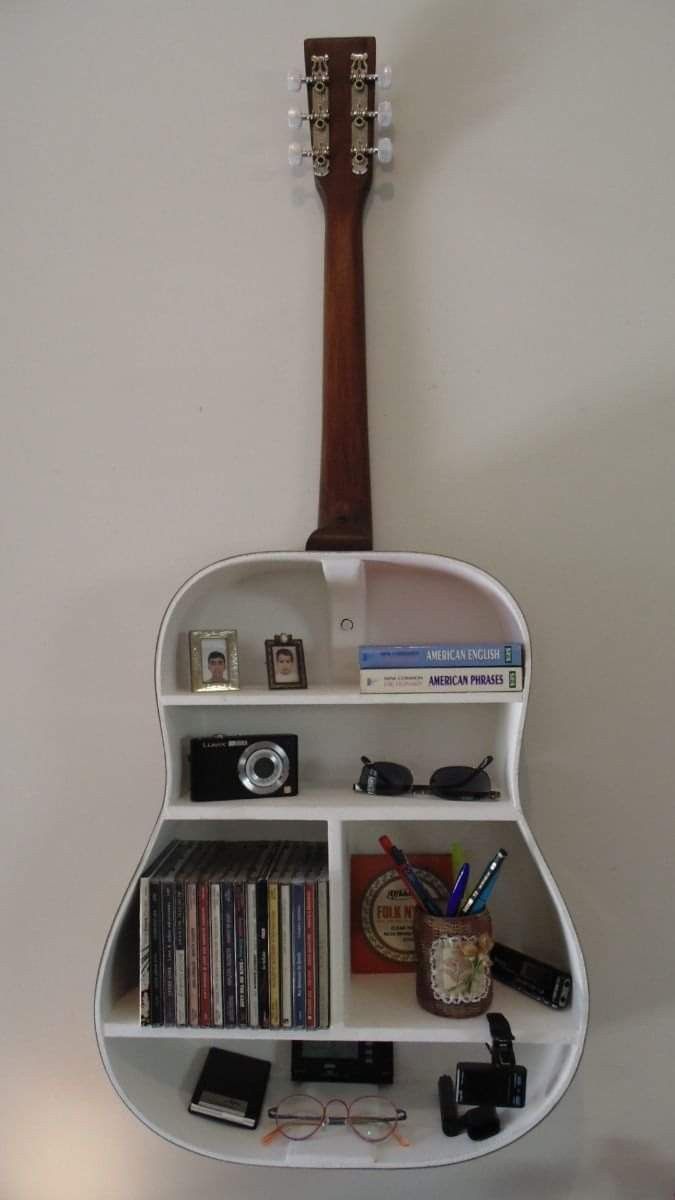 a guitar shaped shelf with books, cd's and other items on it in front of a white wall