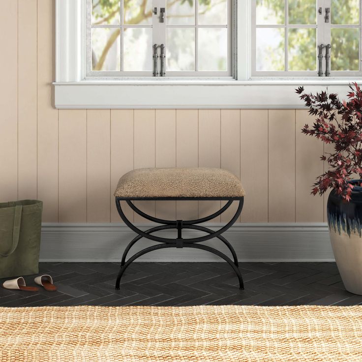 a small bench in front of a window next to a potted plant