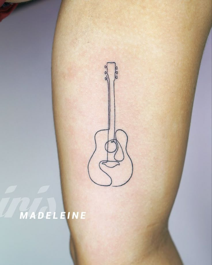 a tattoo on the leg of a woman with a guitar in her left arm,