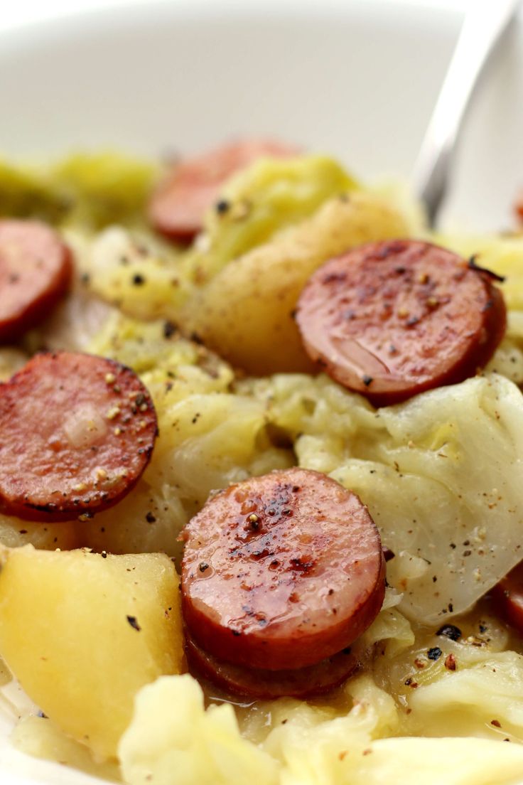 a white bowl filled with potatoes and sausage