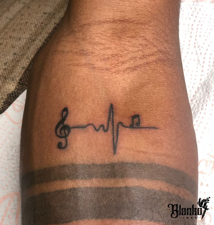 a person with a tattoo on their arm that has music notes in the shape of a heartbeat