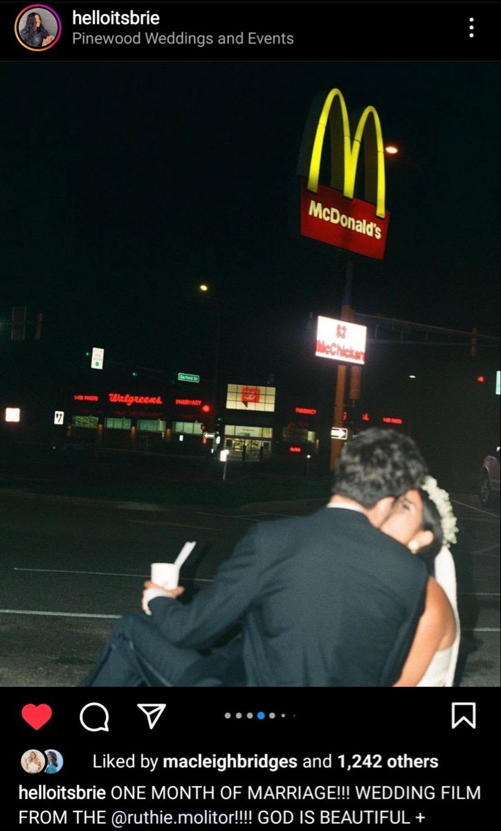 a man and woman kissing in front of a mcdonald's restaurant sign at night