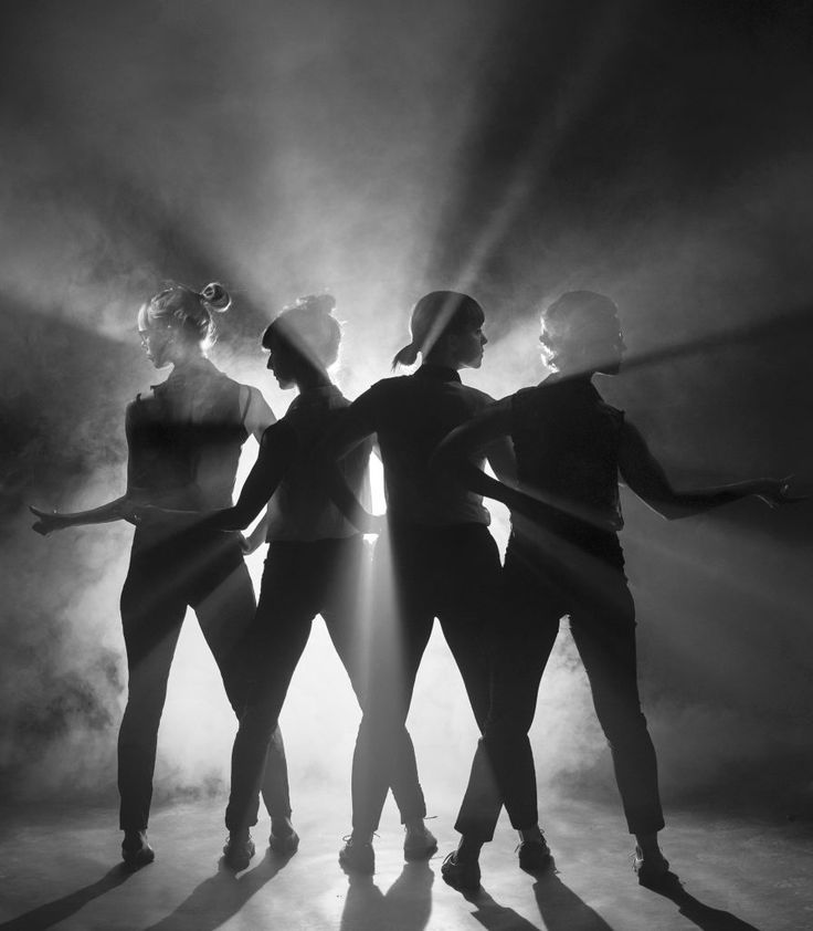 three women are standing in the spotlight with their arms around each other