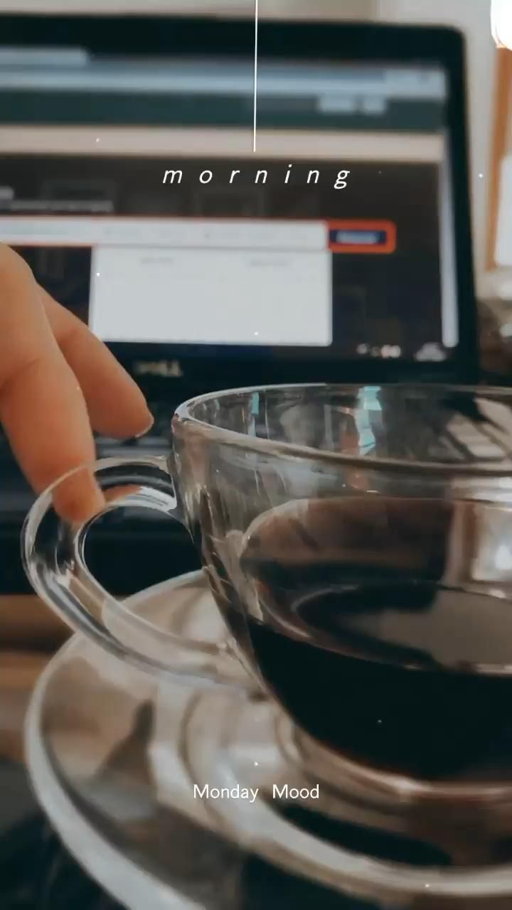 a person is holding a cup of coffee in front of a laptop