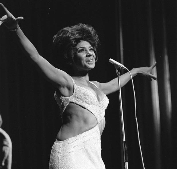 a black and white photo of a woman on stage with her arms in the air