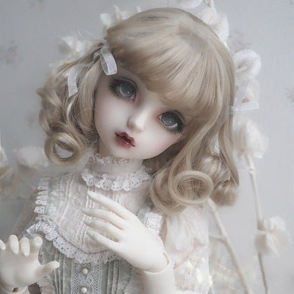 a close up of a doll wearing a dress and holding her hand out to the side