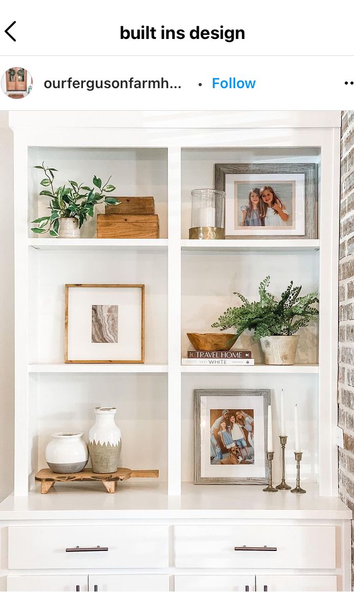 a white bookcase filled with pictures and other items on top of a brick wall