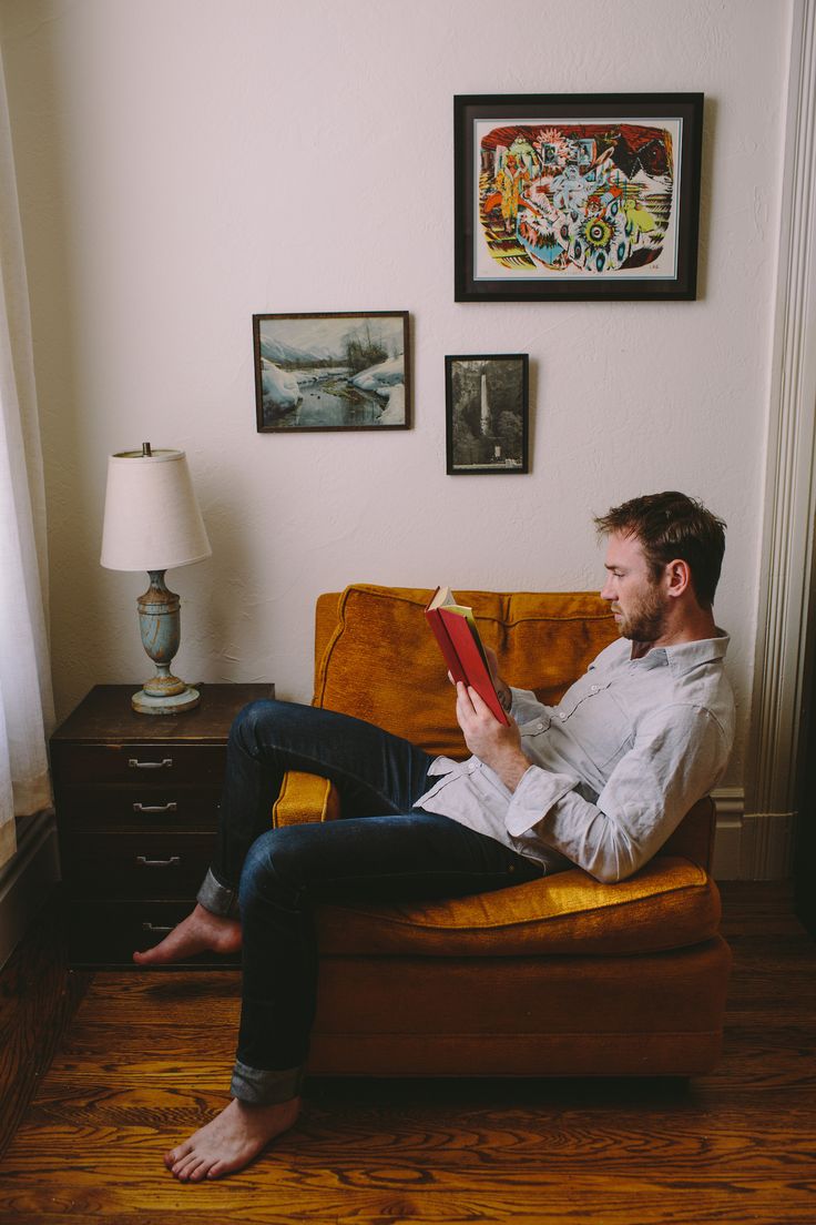 a man sitting on a couch reading a book