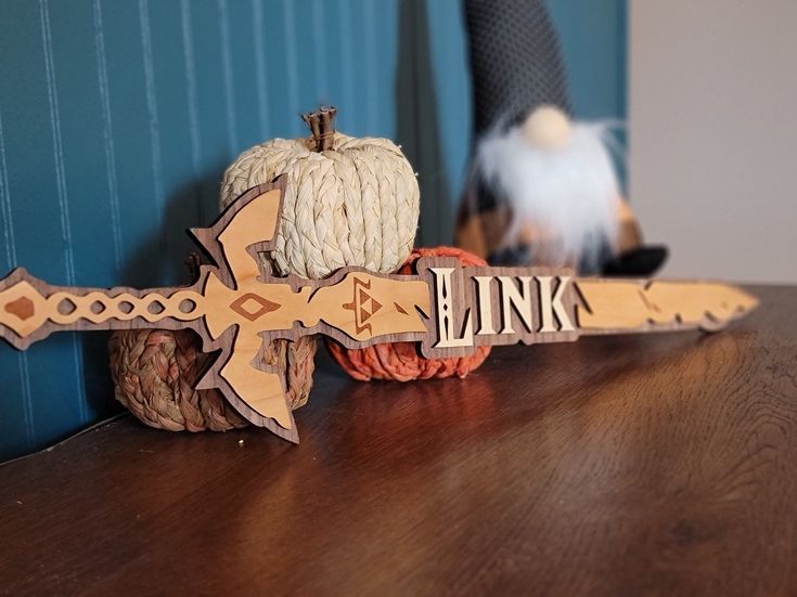 a wooden sign that says link next to some pumpkins and yarn on a table