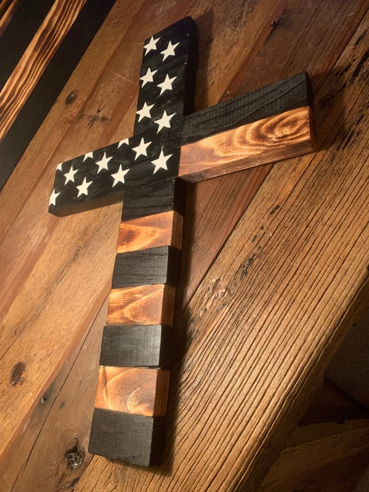 a wooden cross with an american flag painted on it sitting on top of a wood floor