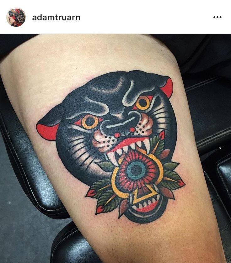 a black cat with red horns and flowers on his leg is seen in this tattoo