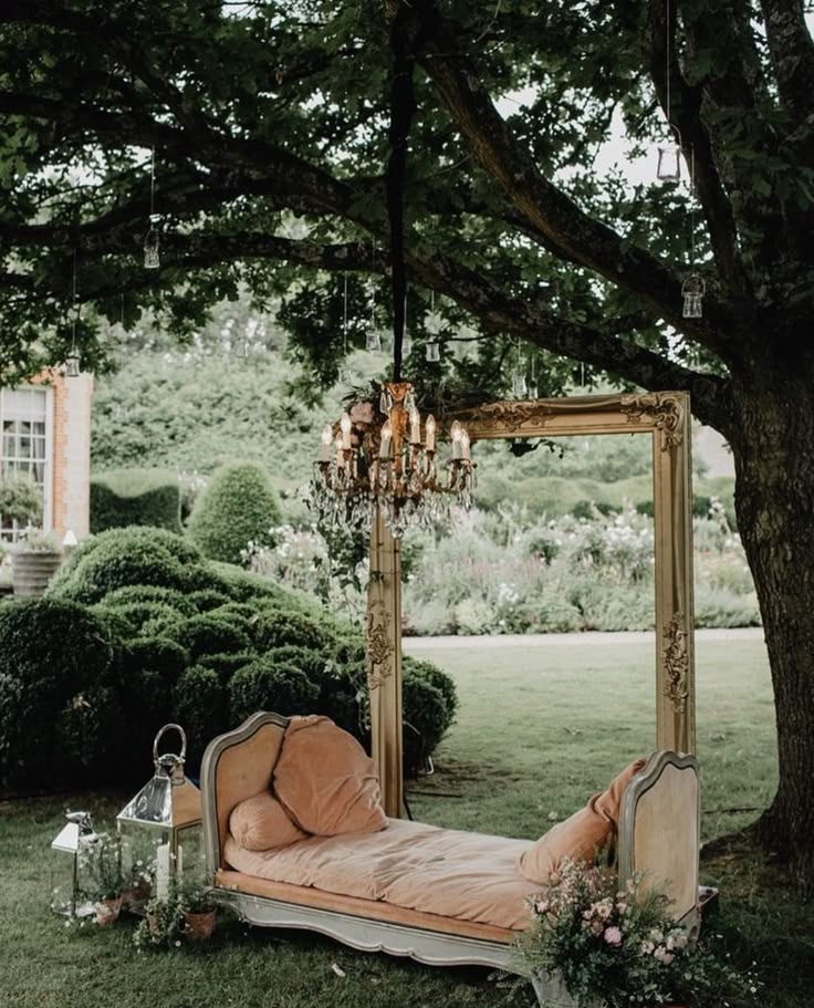 a bed sitting under a tree next to a lush green field