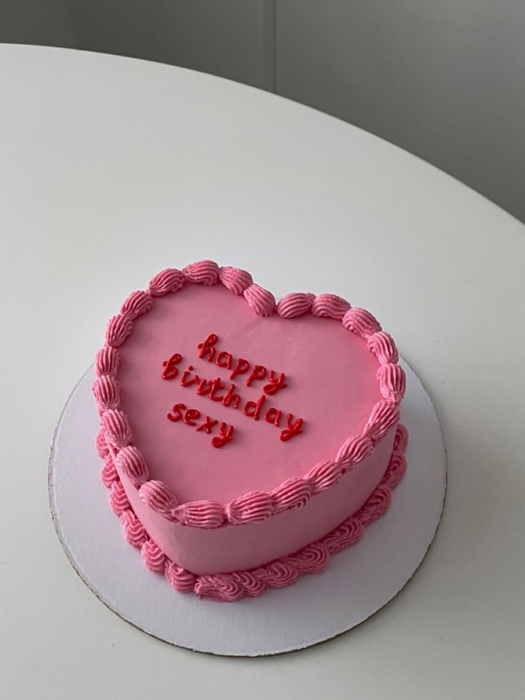 a pink heart shaped birthday cake sitting on top of a white table with the words happy birthday story written on it