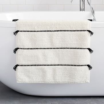 a white bath tub sitting next to a black and white towel on top of it