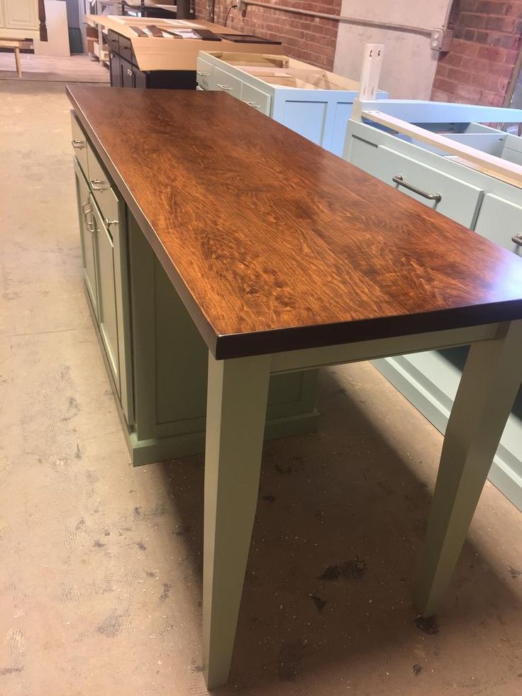 a kitchen island made out of wood in a room with blue cabinets and counter tops