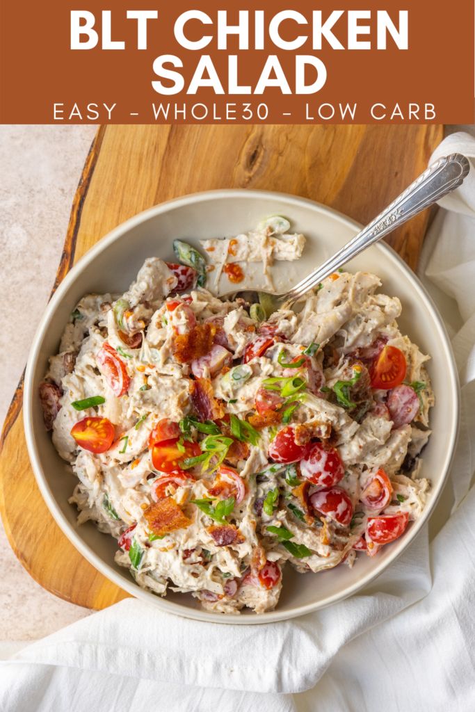 a white bowl filled with chicken salad on top of a wooden cutting board