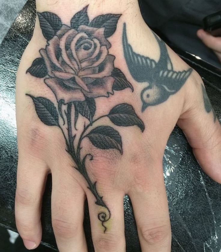 a person's hand with a rose tattoo on it and a bird flying by