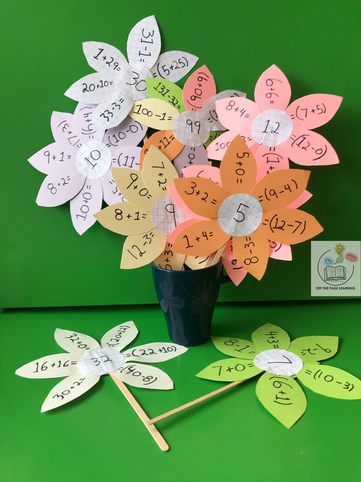 a vase filled with lots of paper flowers on top of a green table next to stickers