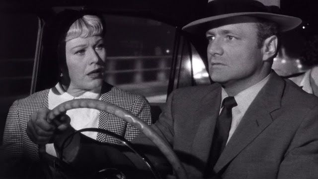 a man driving a car with a woman behind the steering wheel