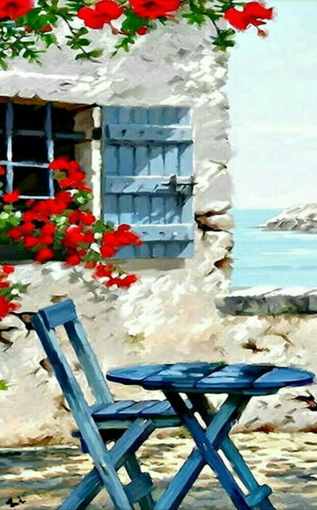 two chairs and table in front of an old building with red flowers on the windowsill