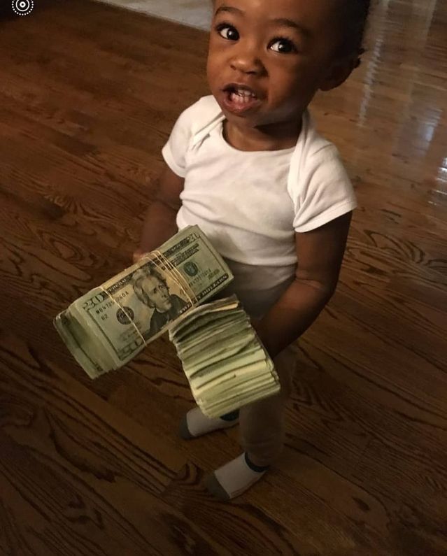 a baby is holding money in one hand and looking at the camera