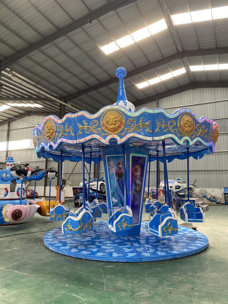 a merry go round ride in the middle of an indoor area with other rides around it