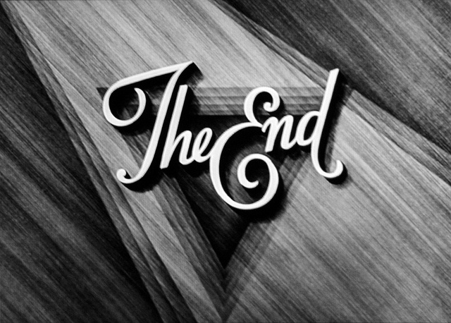 the end logo in black and white with wood grained paper behind it, as seen from above