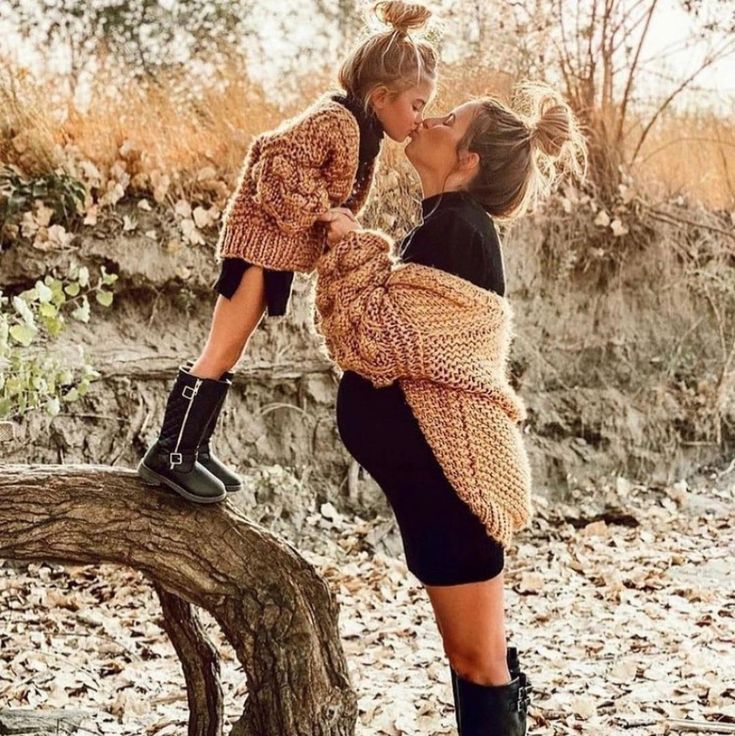 two women kissing each other while standing on a tree branch