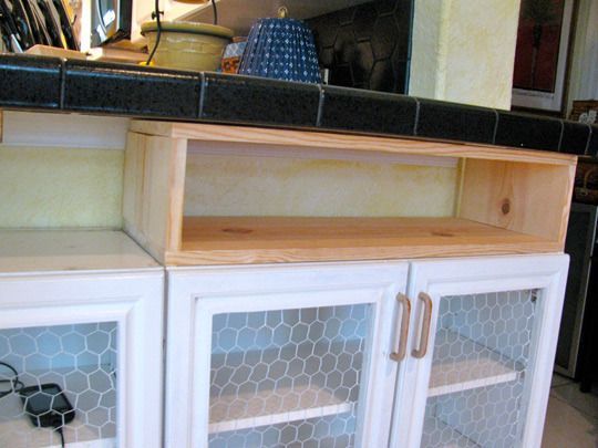 a kitchen counter with chicken wire on the top and glass doors in front of it