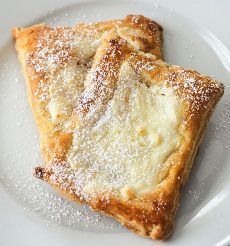 two pieces of pastry on a plate with powdered sugar sprinkled on top