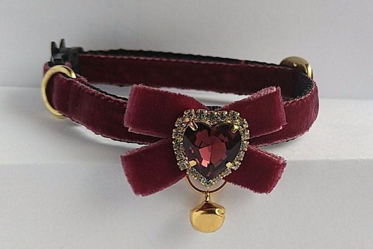 a red velvet collar with a heart shaped brooch attached to it's side