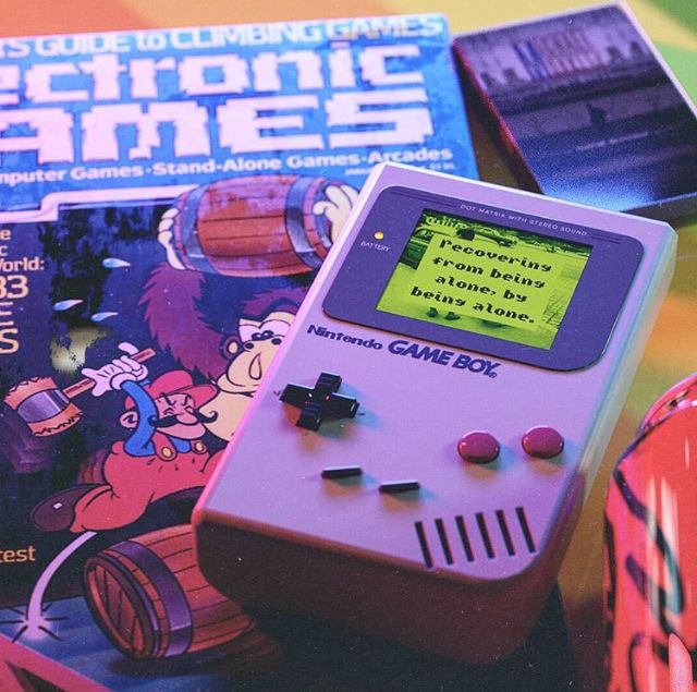 an old gameboy sitting on top of a table next to other games and books