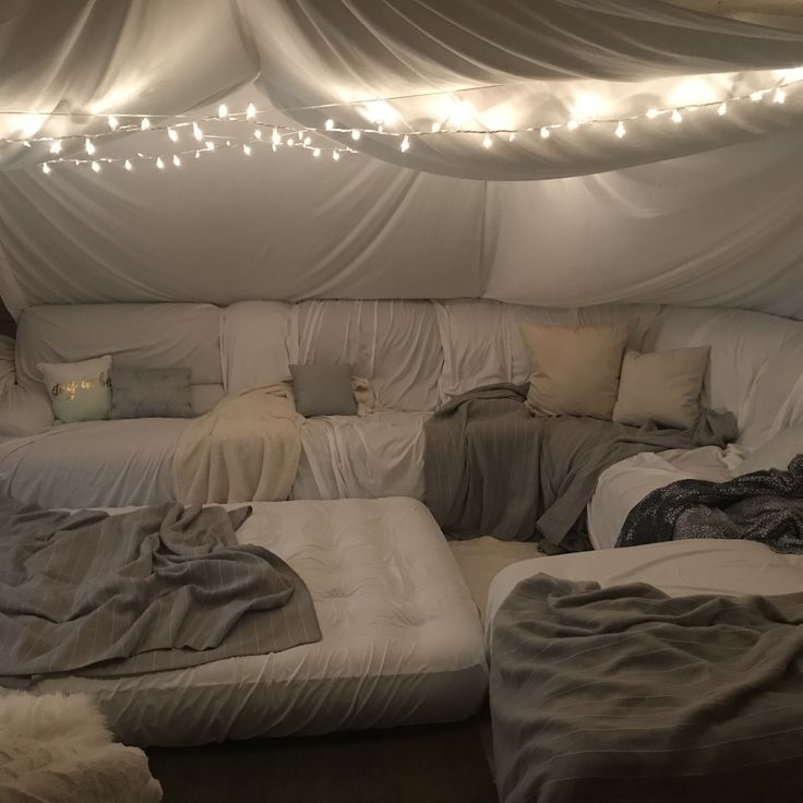 an unmade bed in a room with lights on the ceiling and sheets draped over it