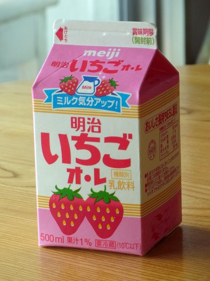 a carton of strawberry milk sitting on top of a wooden table