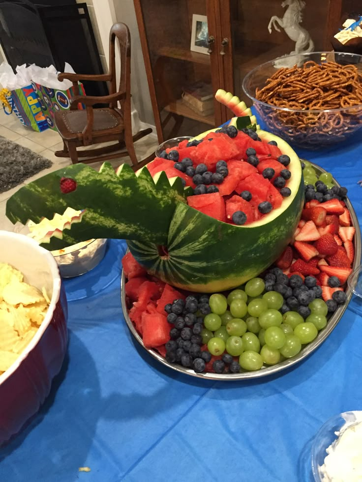 a watermelon boat made out of fruits and vegetables on a blue table cloth