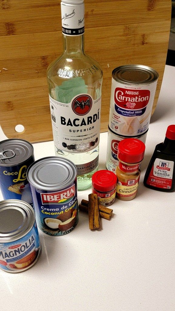 the ingredients to make an apple cider are displayed on a white countertop, including cinnamon sticks and spices