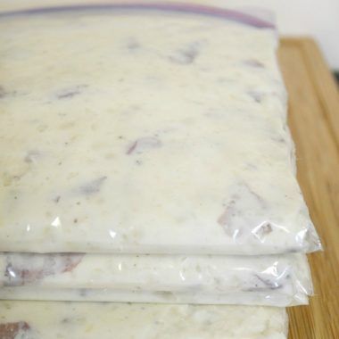 three bags of food sitting on top of a wooden cutting board