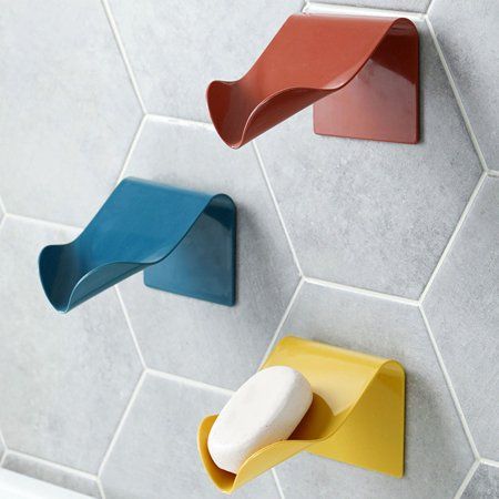 three colorful soap dispensers mounted on the wall next to a bathtub