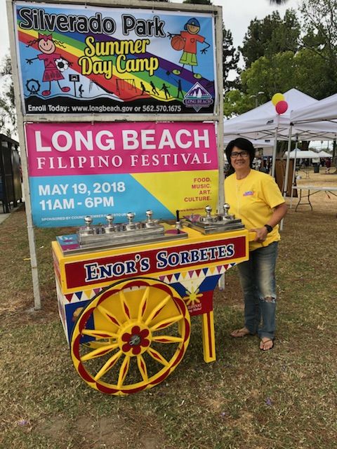 a woman standing in front of a sign for the long beach fair on may 19, 2013