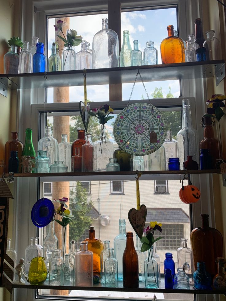 the shelves are filled with glass bottles and vases