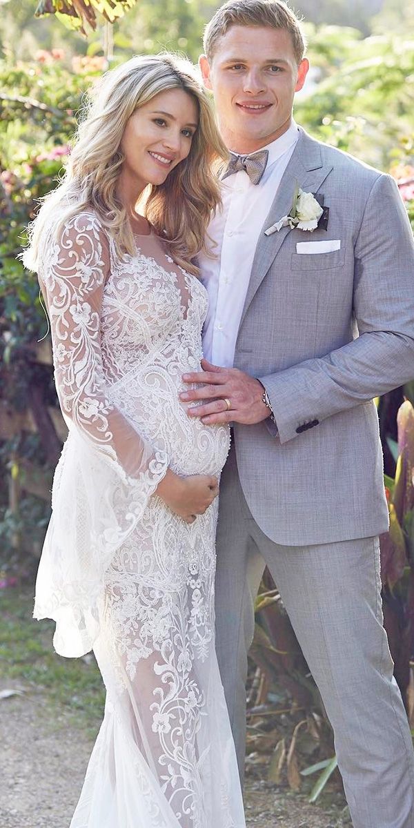 a man and woman in wedding attire posing for a photo together with flowers behind them