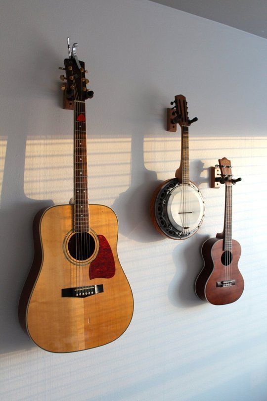 three guitars are hanging on the wall next to each other