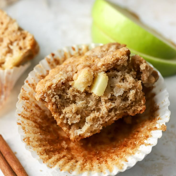 two muffins sitting on top of each other next to an apple and cinnamon stick