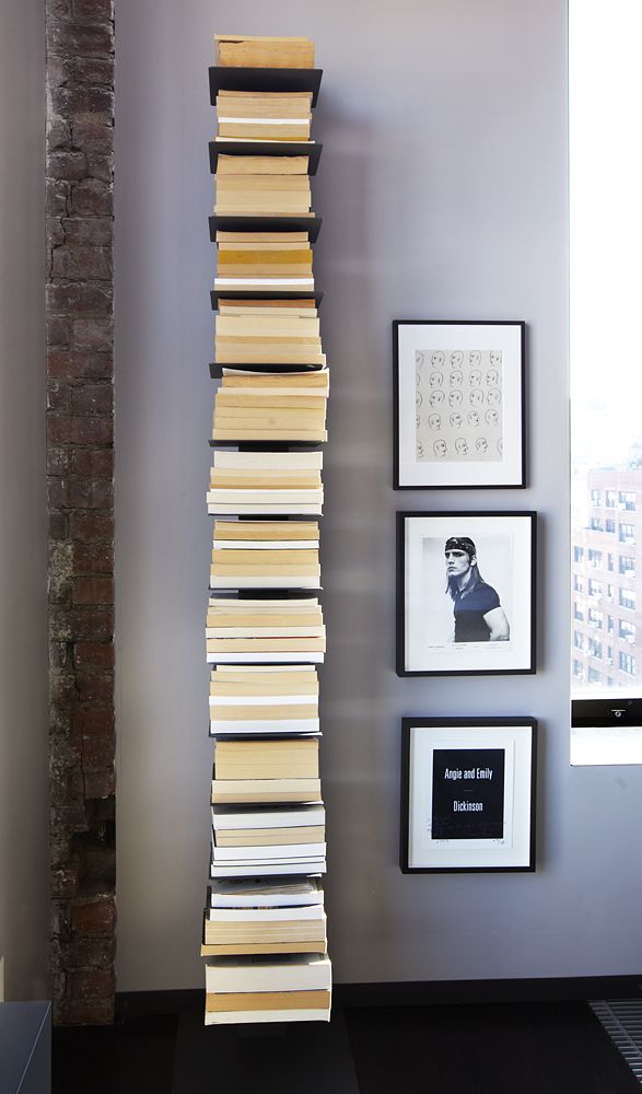 a tall stack of books sitting on top of a floor next to pictures and frames