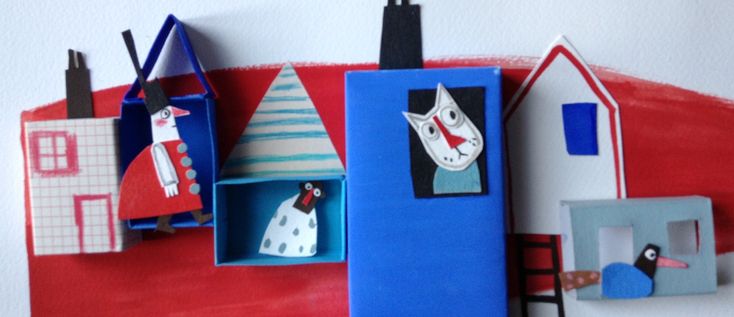 some paper houses are on the wall and one is painted red, white and blue