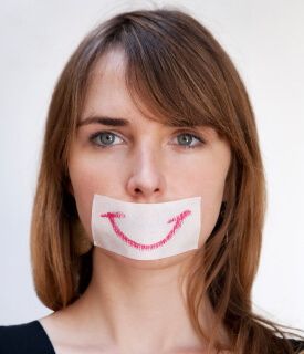 a woman with a piece of paper taped to her mouth that has a smile drawn on it