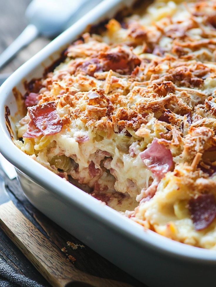 a casserole with ham and cheese in a white dish on a wooden table