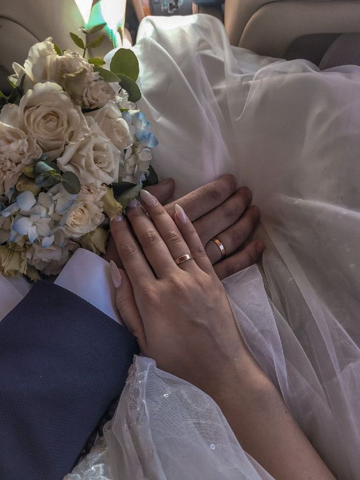 the bride and groom are holding hands on their wedding day in the back seat of a car